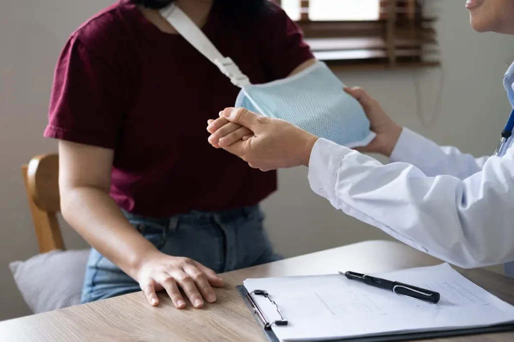 Doctor helps a patient with her arm in a sling