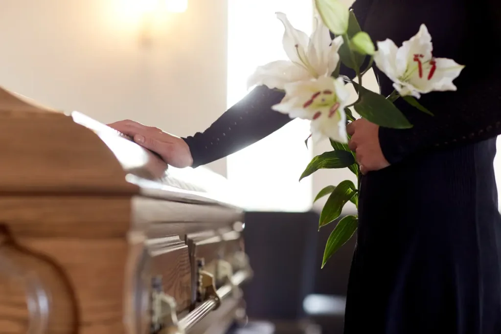 Mourner places lilies on a casket