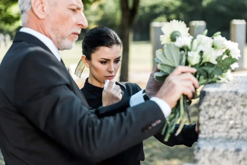 Family members place flowers at a grave
