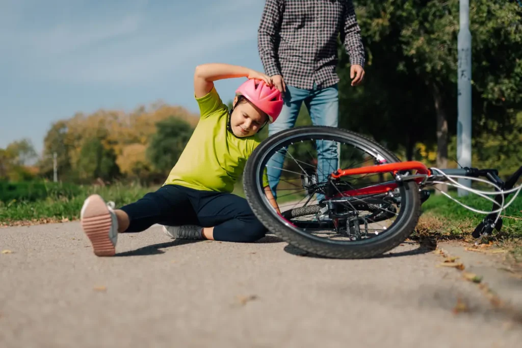 Child falls off a bike on a path