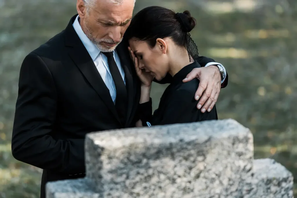 Man comforts a grieving woman at a memorial