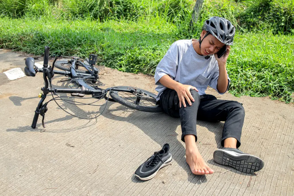 Injured cyclist sits on the pavement and calls for help