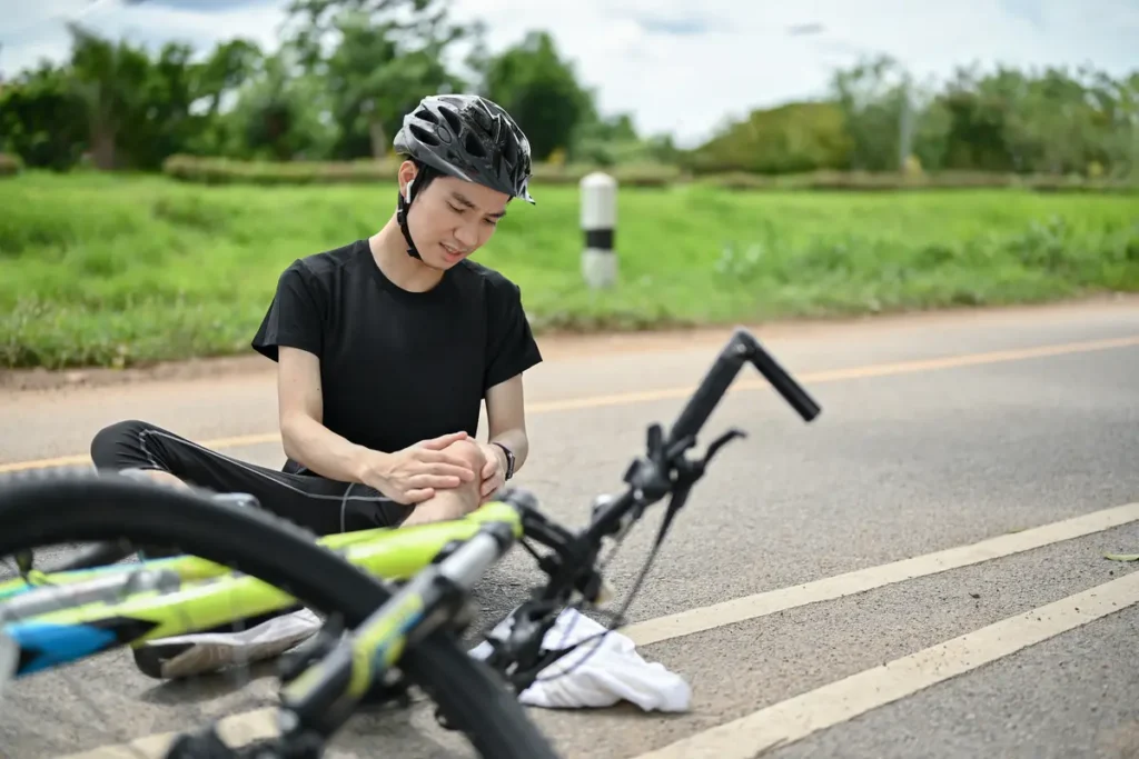 Injured cyclist checks her knee next to her bike