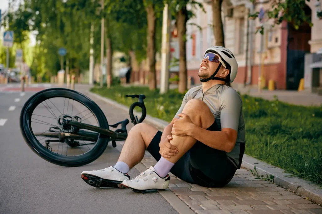 Cyclist holds an injured knee after a fall on a bike path