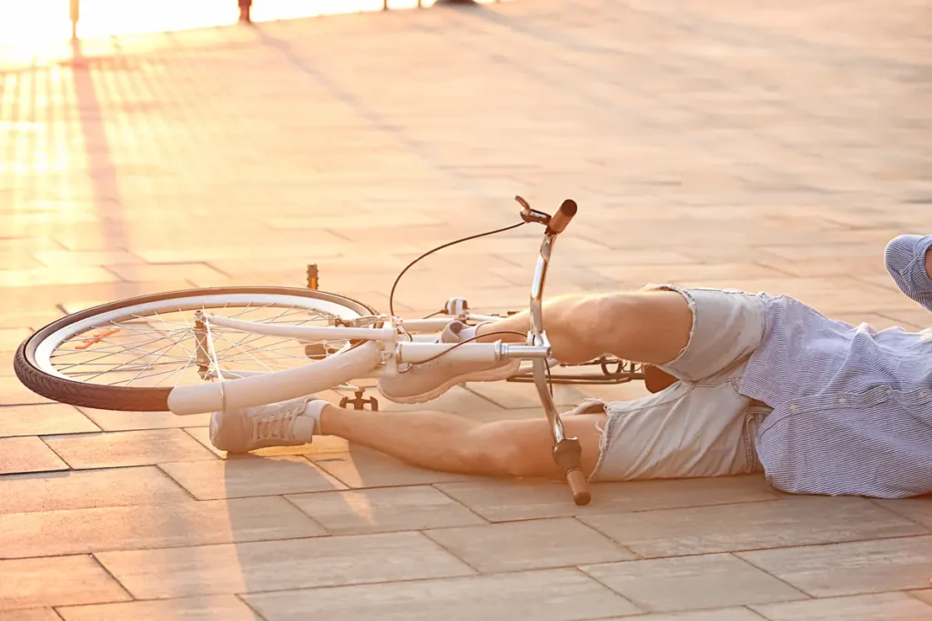 Cyclist lying on the pavement with his bike