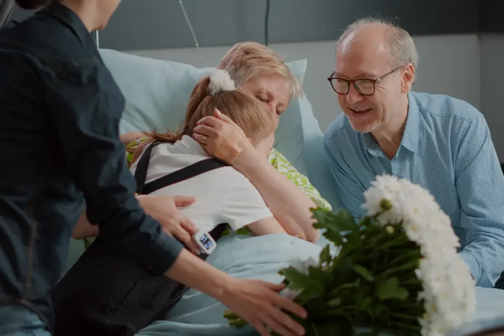 Family comforts a senior woman in a hospital bed
