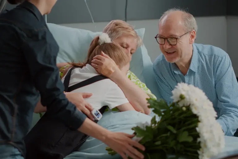 Family comforts a senior woman in a hospital bed