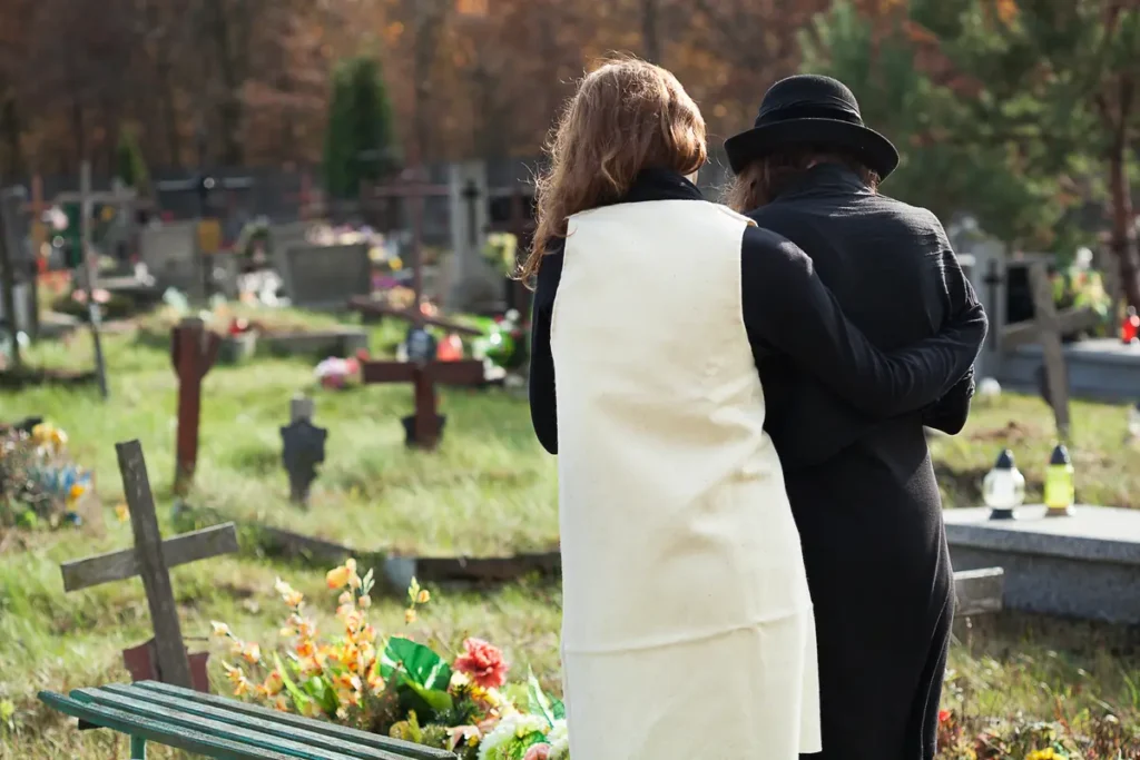 Two people embrace in a cemetery