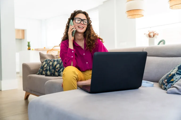 Woman on the phone with an insurer, comparing quotes on a laptop at home