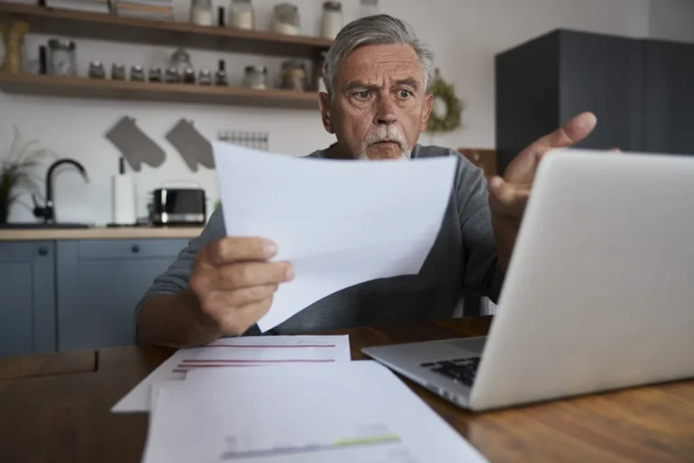 Man looks over medical bills at his laptop after a car accident