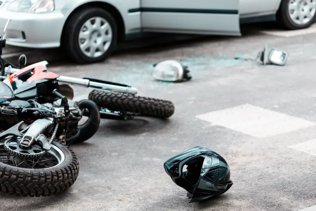 Motorcycle on its side after a crash with a car, helmet on the road