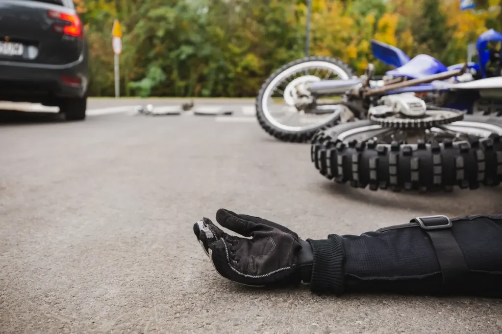 Downed motorcycle and a rider's gloved hand on the road