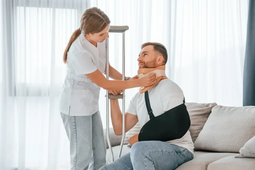 Caregiver helps a man wearing a neck brace and arm sling