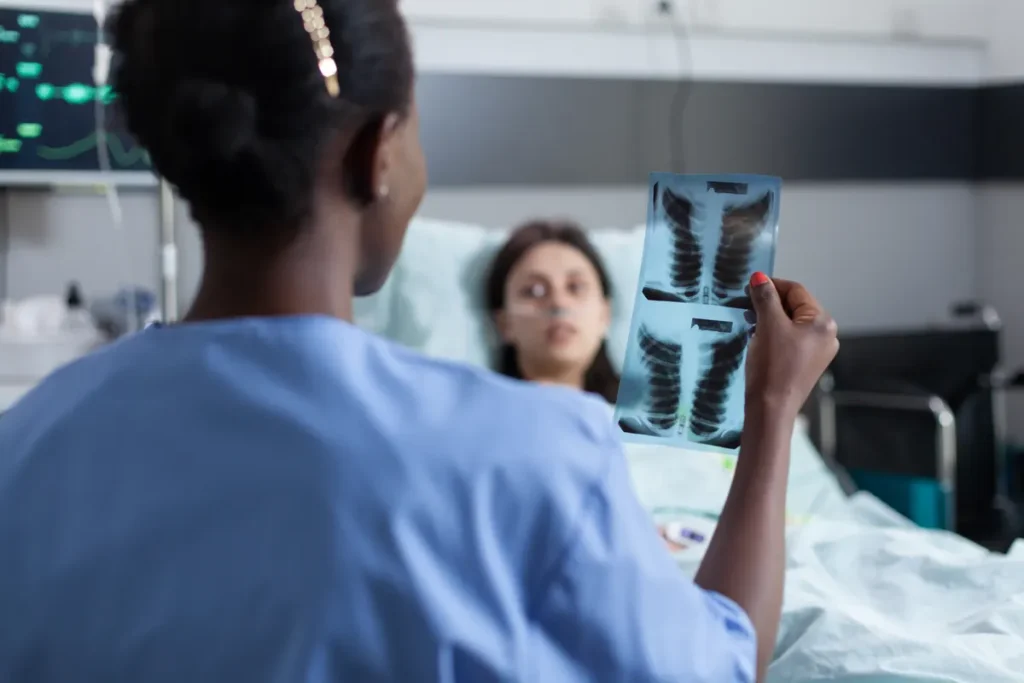 Nurse reviews a chest X-ray with a patient in a hospital bed
