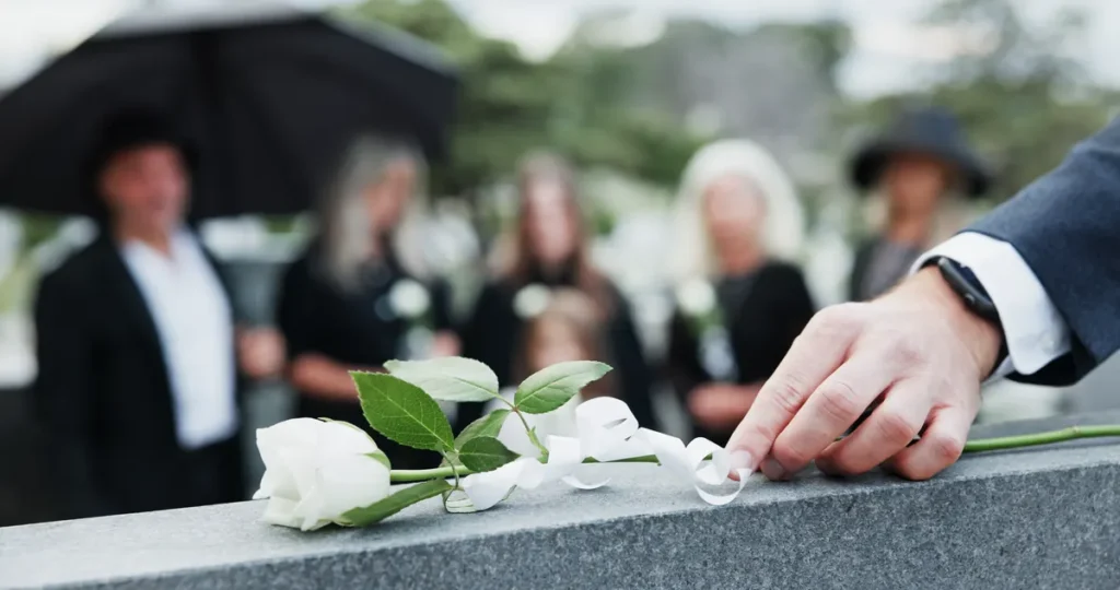 Mourner places a white rose on a headstone