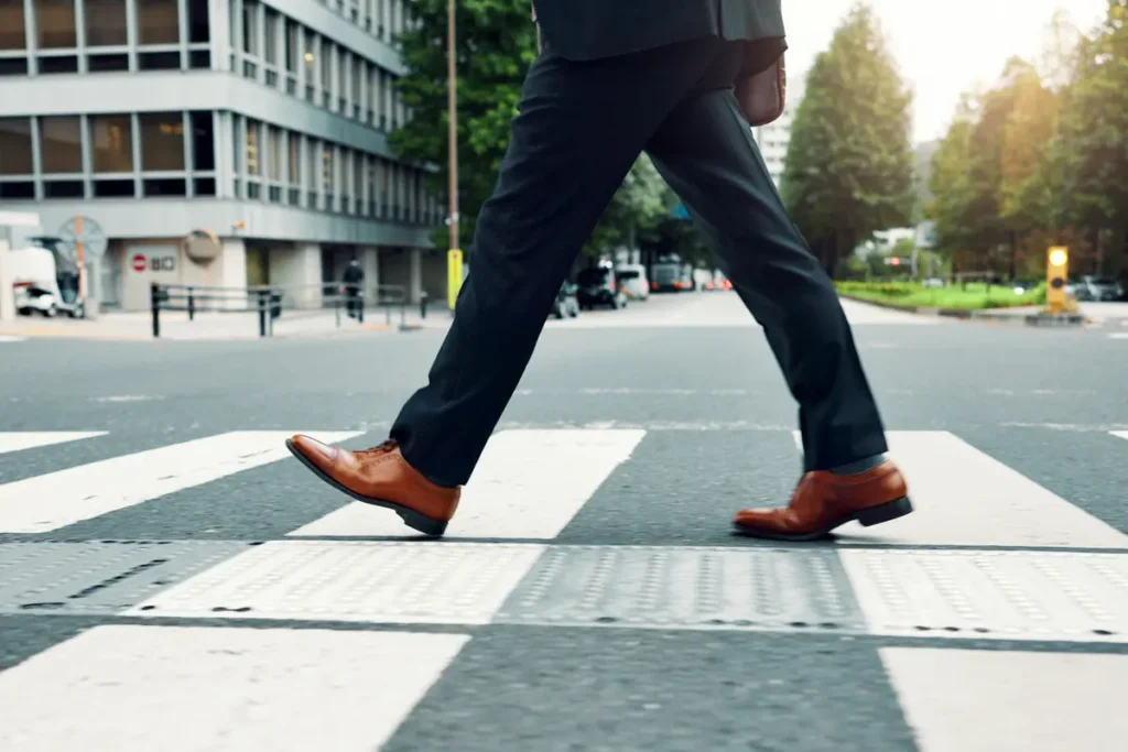 Person in a suit walking across a city crosswalk