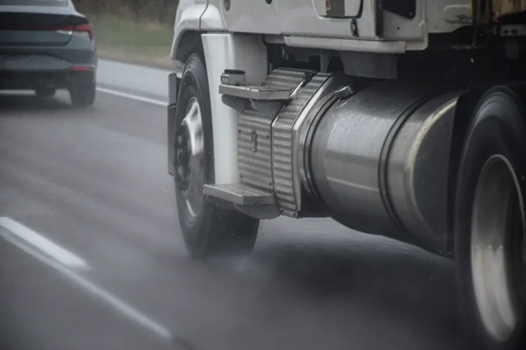 Truck wheels throw spray on a wet highway