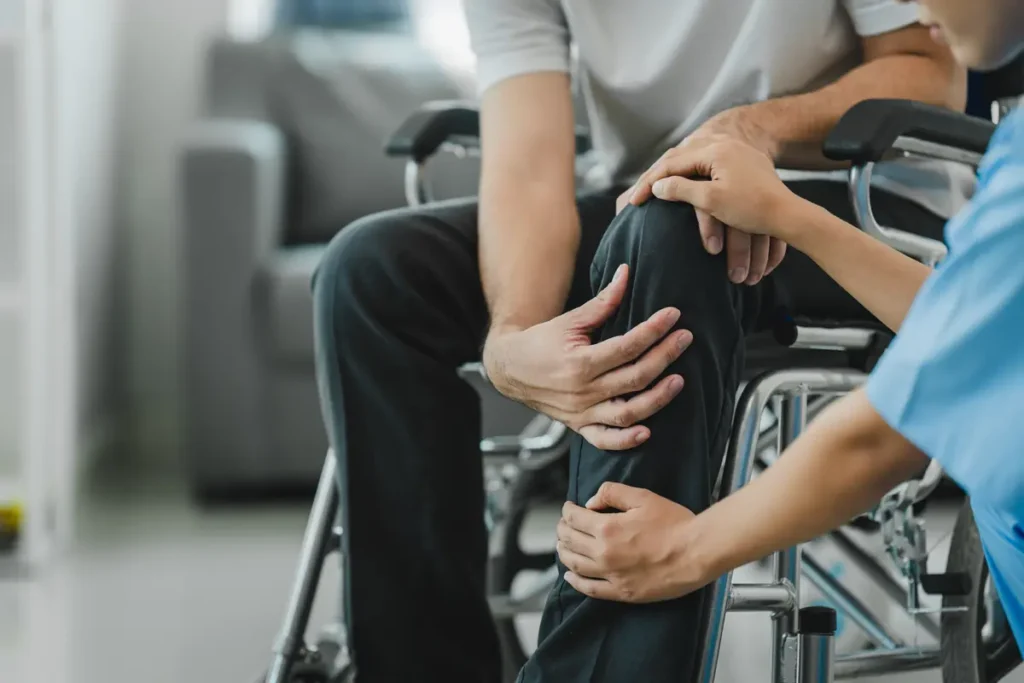 Patient in a wheelchair with a caregiver's hand on his knee