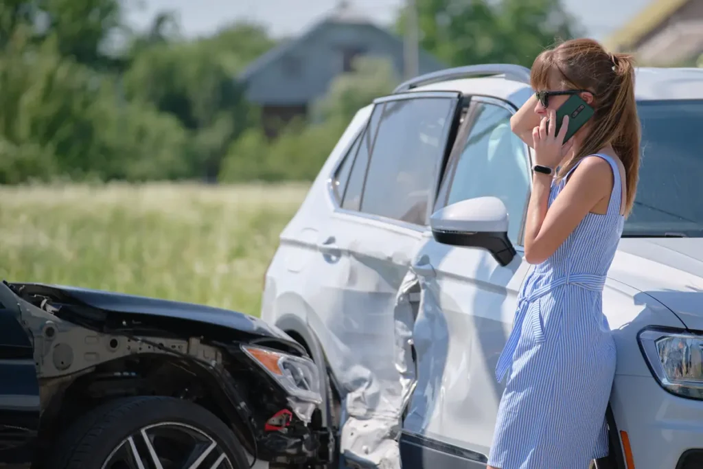 Woman on the phone next to her damaged car