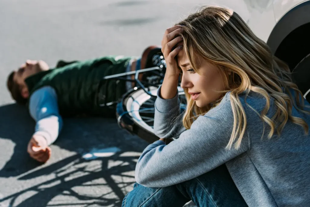 Worried woman sits near an injured cyclist