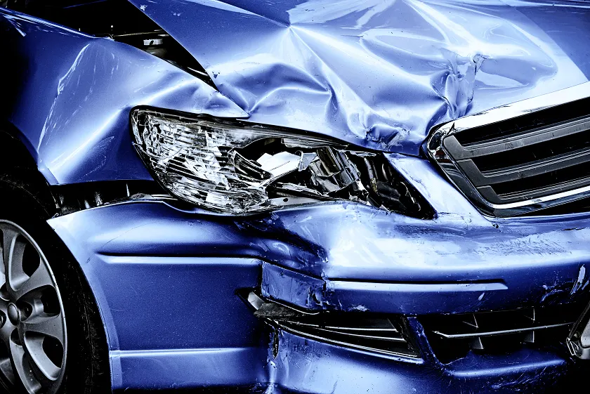 Close-up of a car's crushed front bumper and headlight after a crash