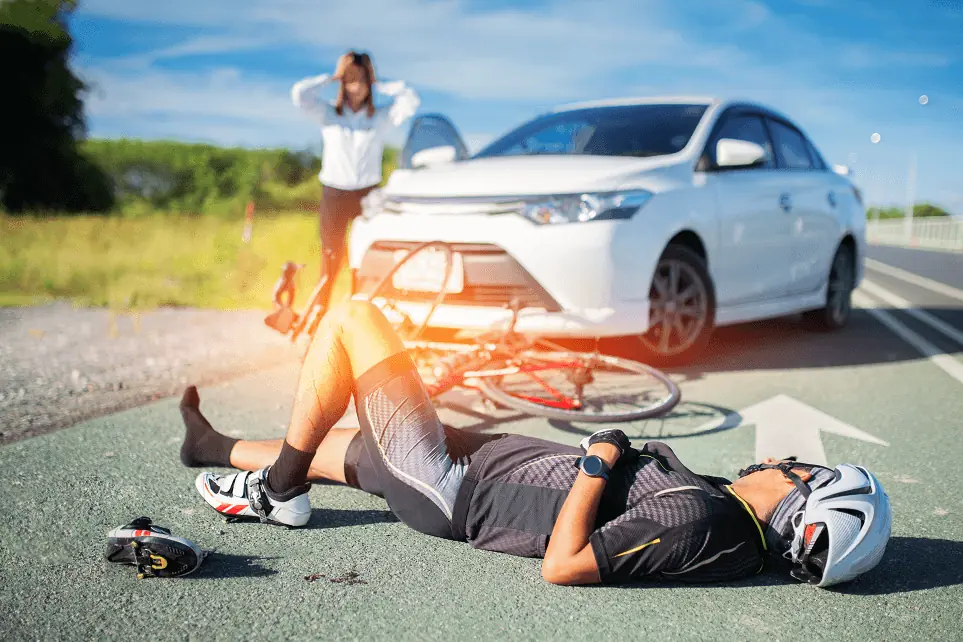 Cyclist on the ground after being hit by a car