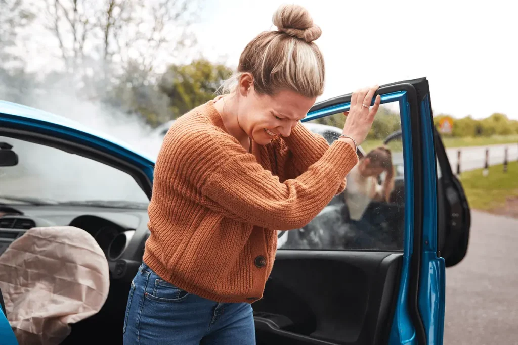 Driver holds her neck next to her crashed car