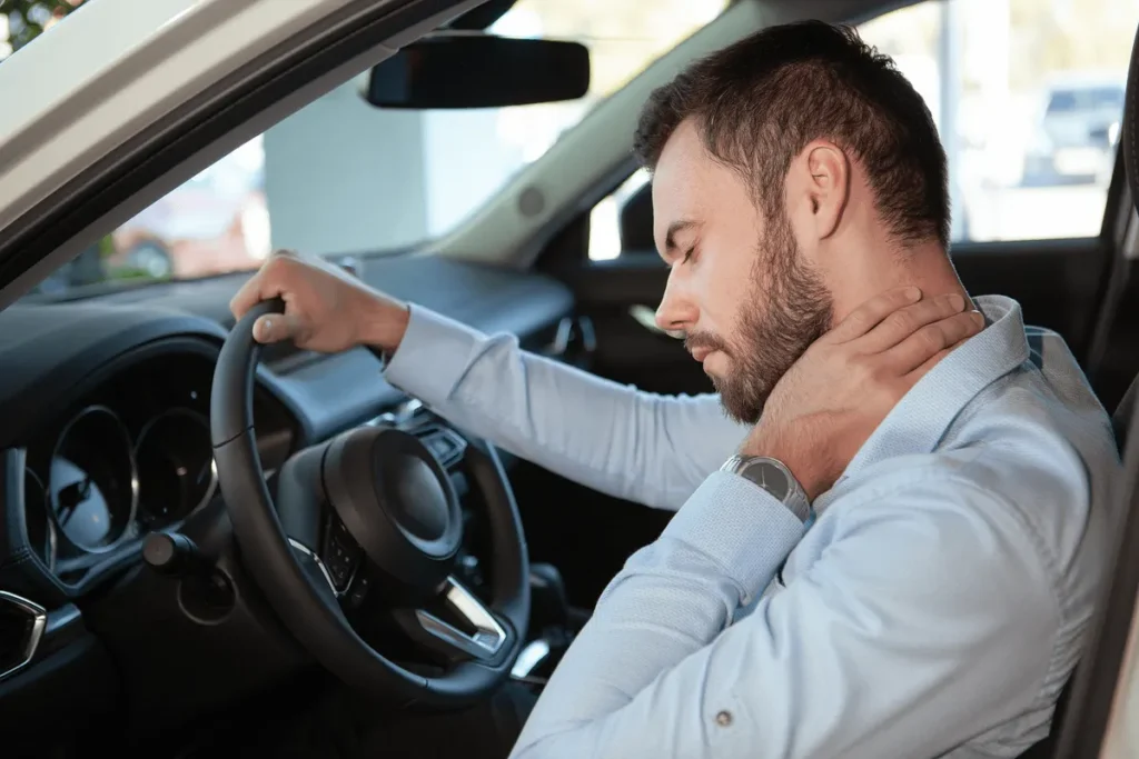 Driver holds his sore neck behind the wheel after a crash